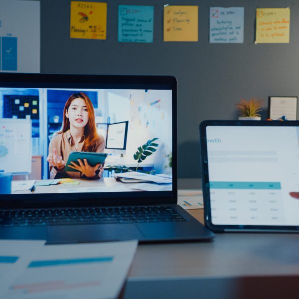 Young Asia financial student ladies watching lesson online and studying with laptop and tablet in living room from home at night. Taking notes while looking at computer screen, Learn online concept.